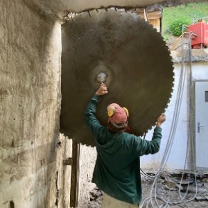 Scie murale au disque diamanté en train de découper une baie dans un mur en béton