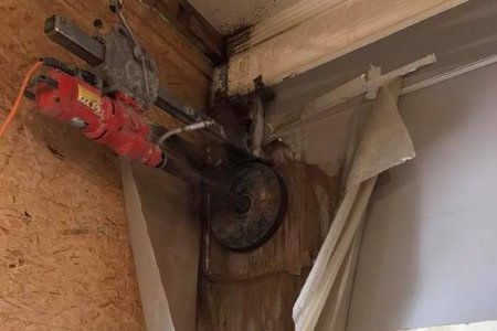 Carotteuse fixée sur un mur en train de percer un passage